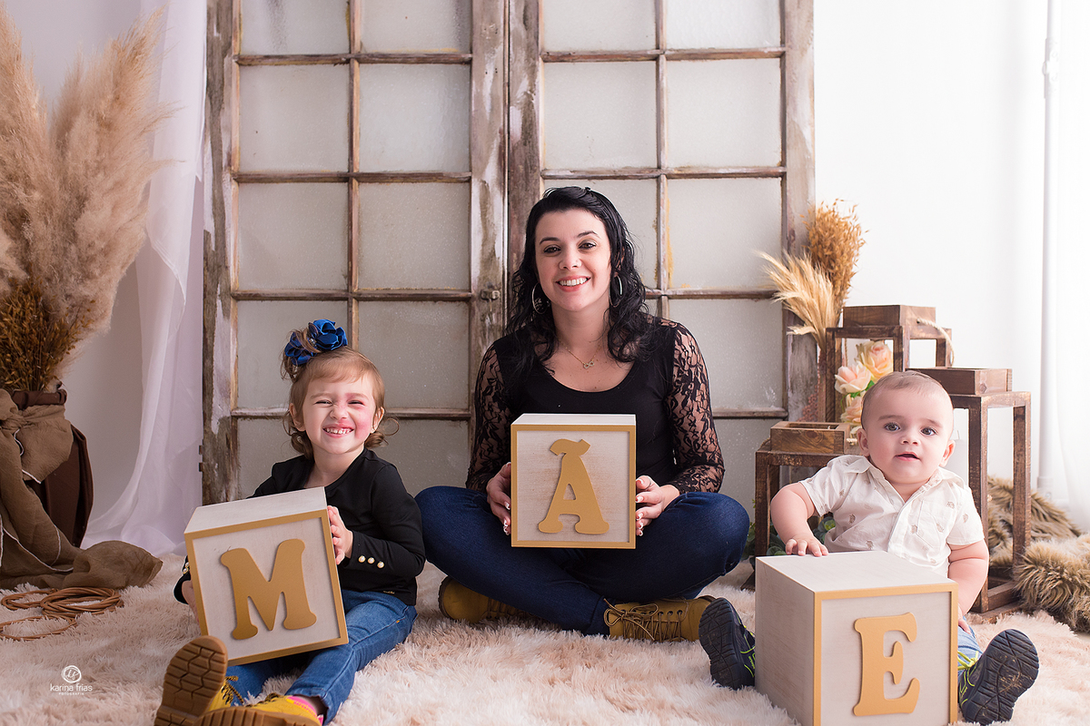 a mae posa com os filhos no cenario de dia das maes