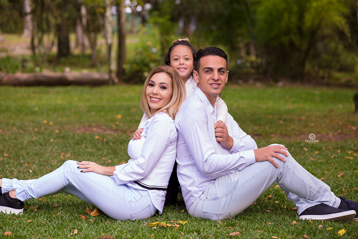 no ensaio externo de familia, a menina abraça os pais