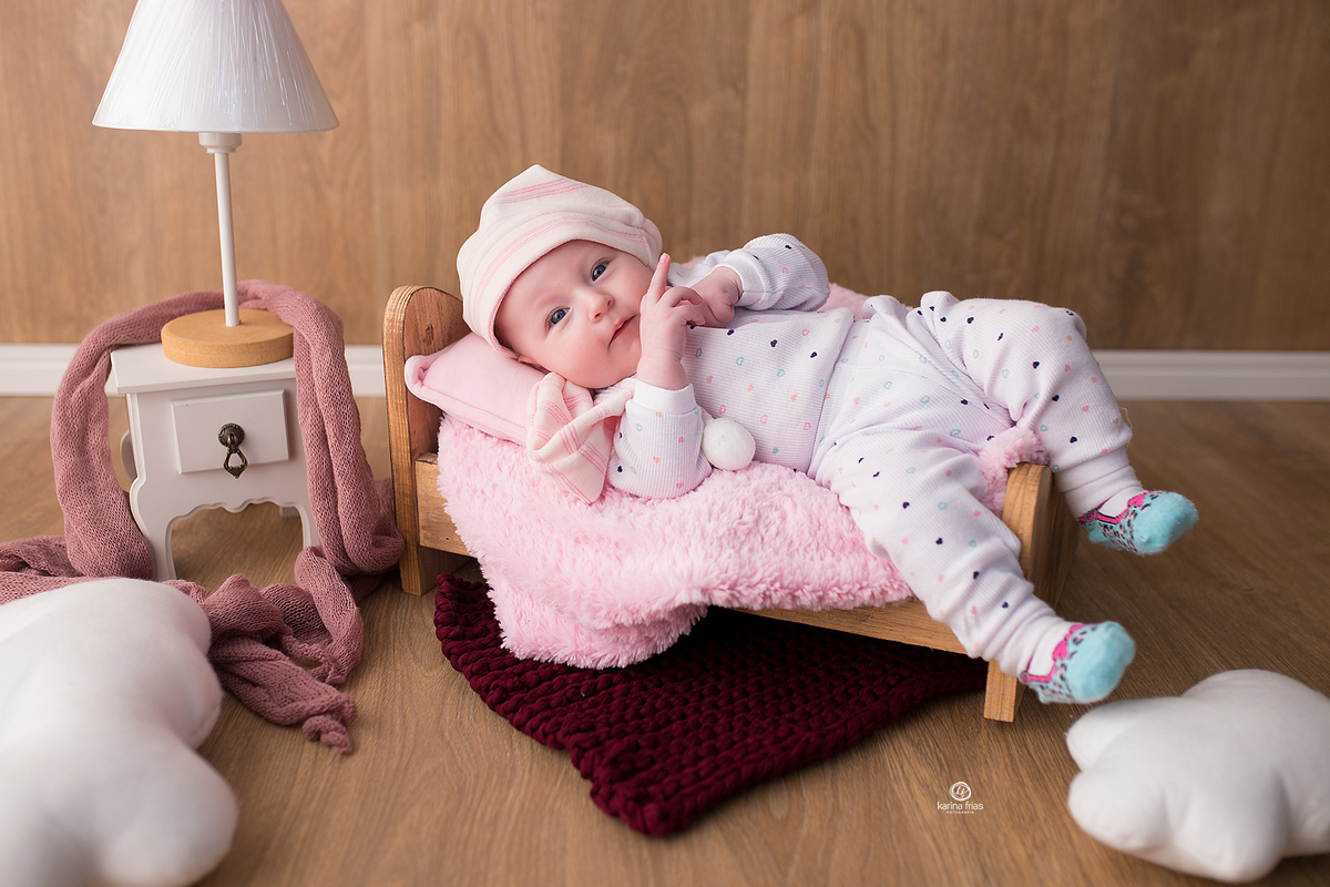 a menina esta deitada na cama para as fotos mensais