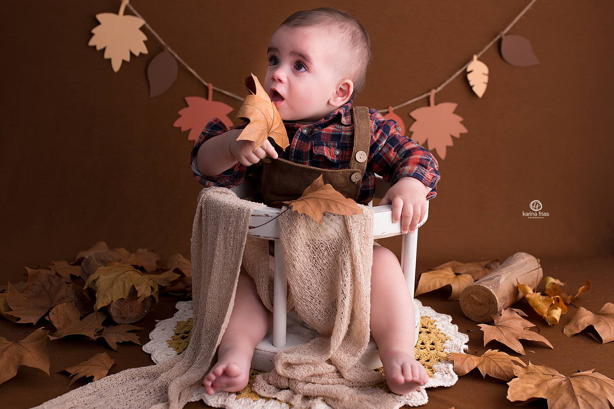 o menino brinca com a folha no cenario de outono