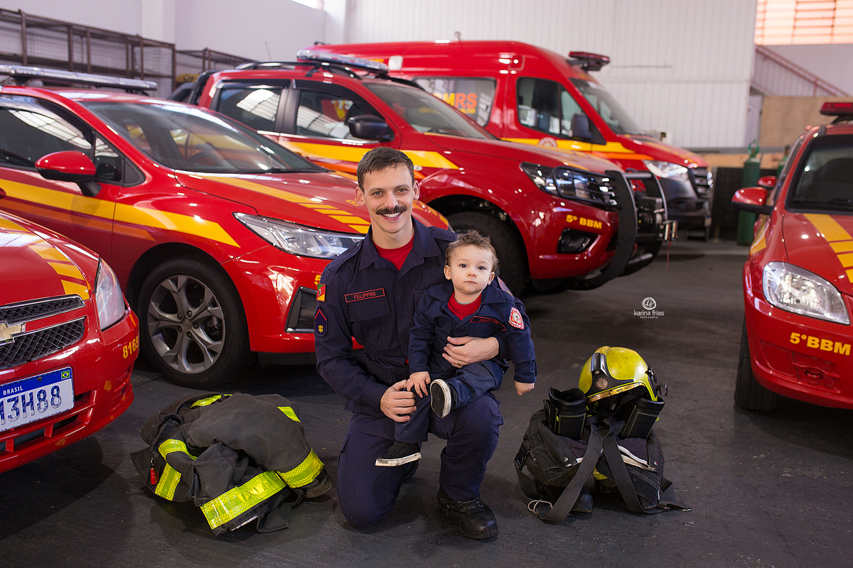 o menino posa com o pai na sessão de fotos no bombeiros