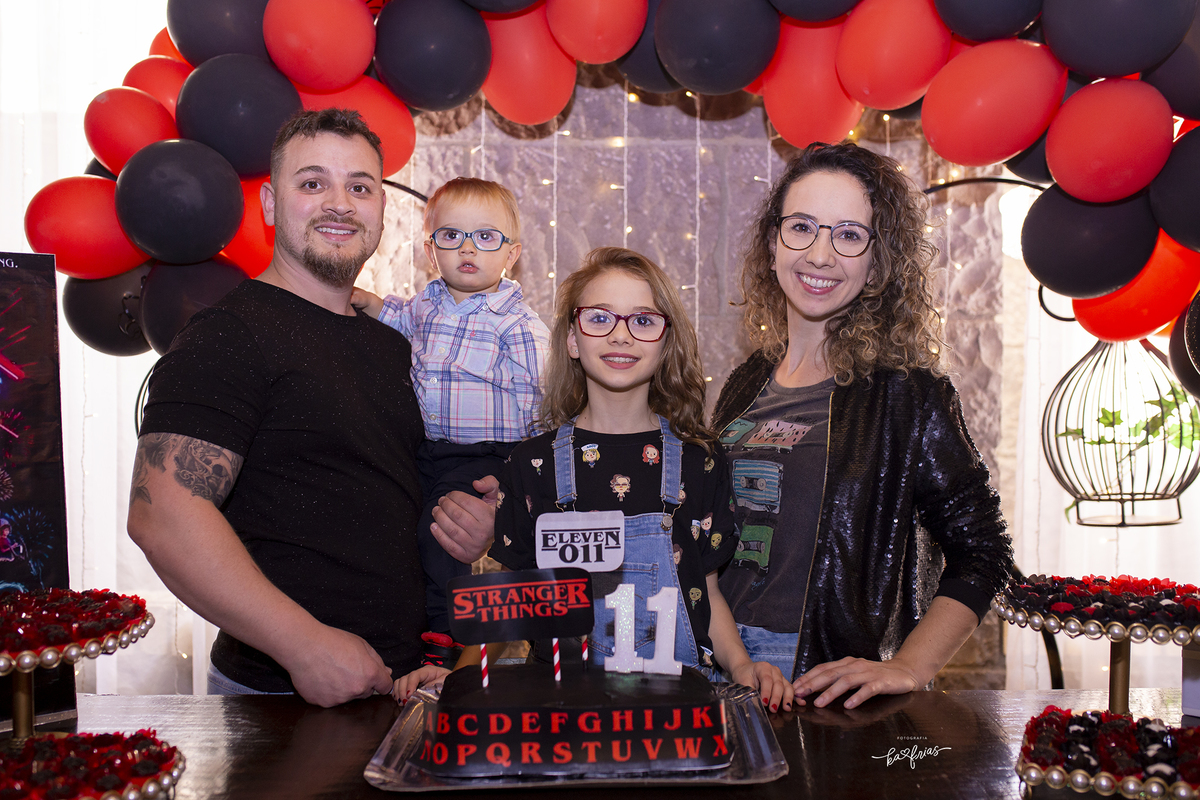 a familia posa na frente da mesa do bolo para as fotos