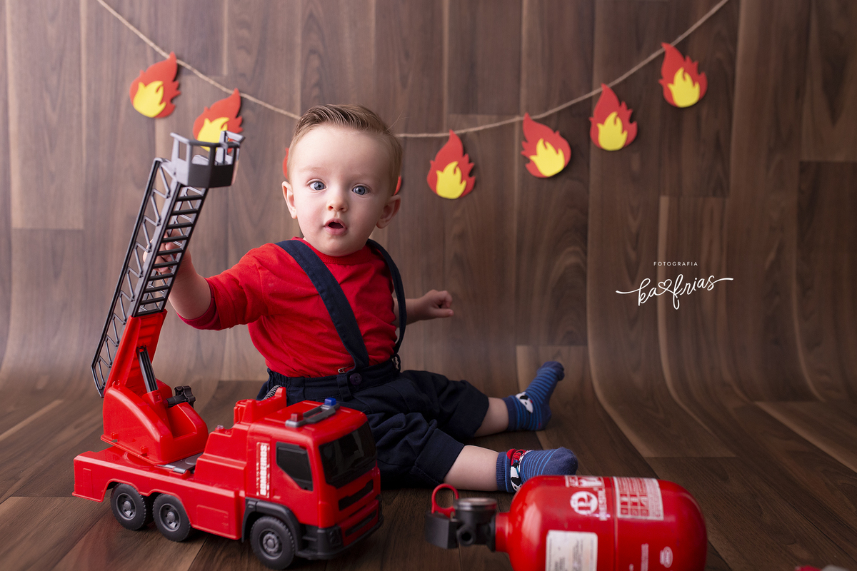 o menino brinca com o caminhao de bombeiros para as fotos infantis