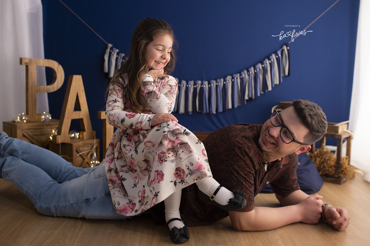a menina senta no pai para as fotos em estudio