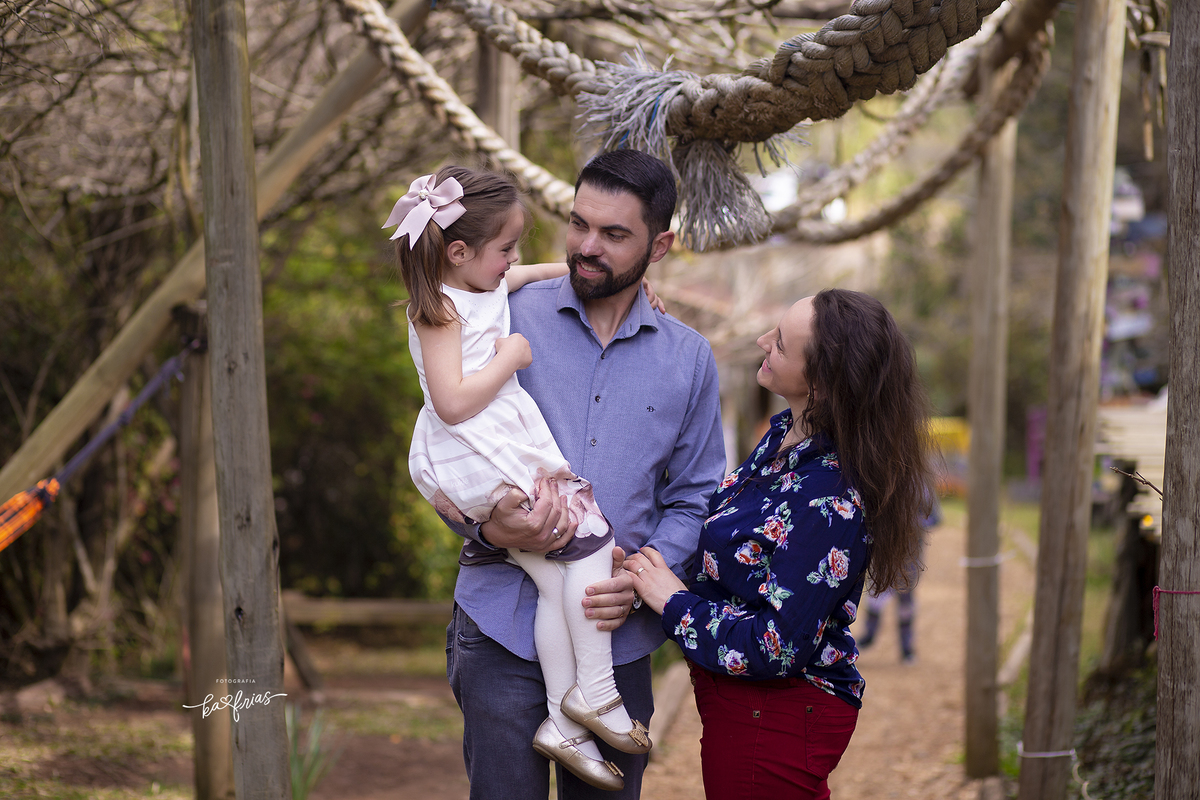 os pais brincam com a filha no ensaio externo