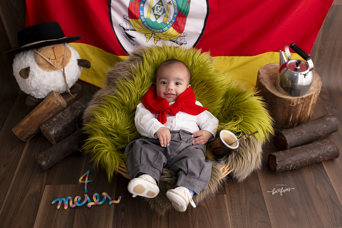 o menino esta vestido de gaucho para as fotos mensais
