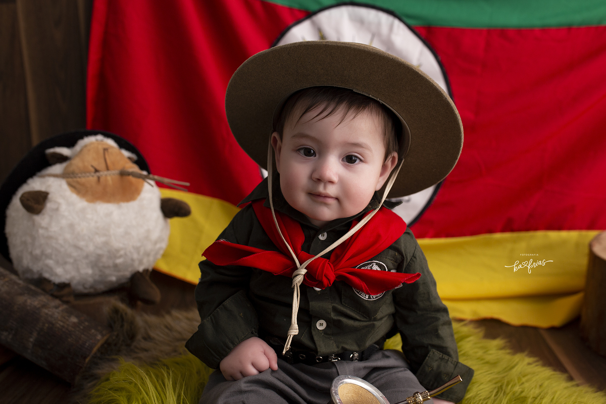 o menino esta vestido de gaucho para as fotos mensais