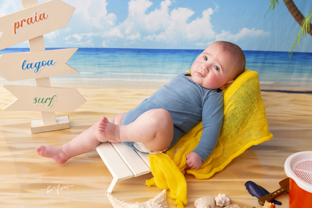 o menino esta deitado na espreguiçadeira para as fotos em estudio