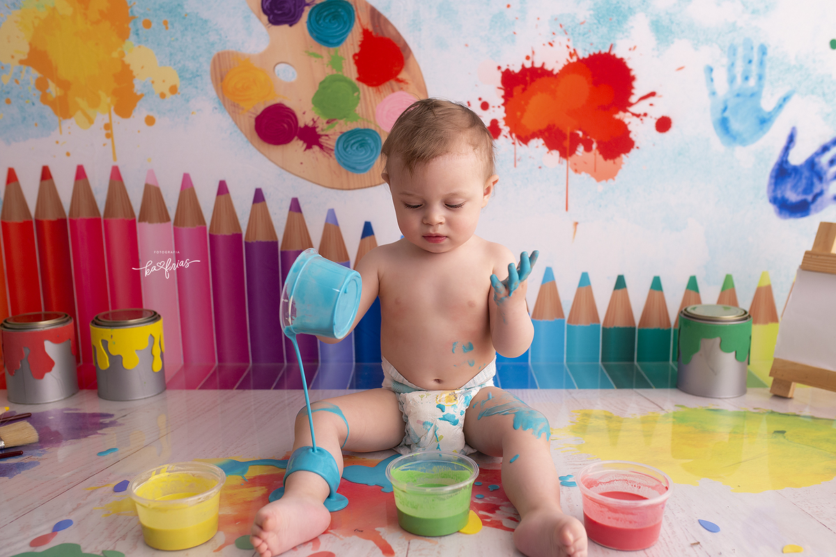 o bebe brinca com as tintas no cenario de aquarela
