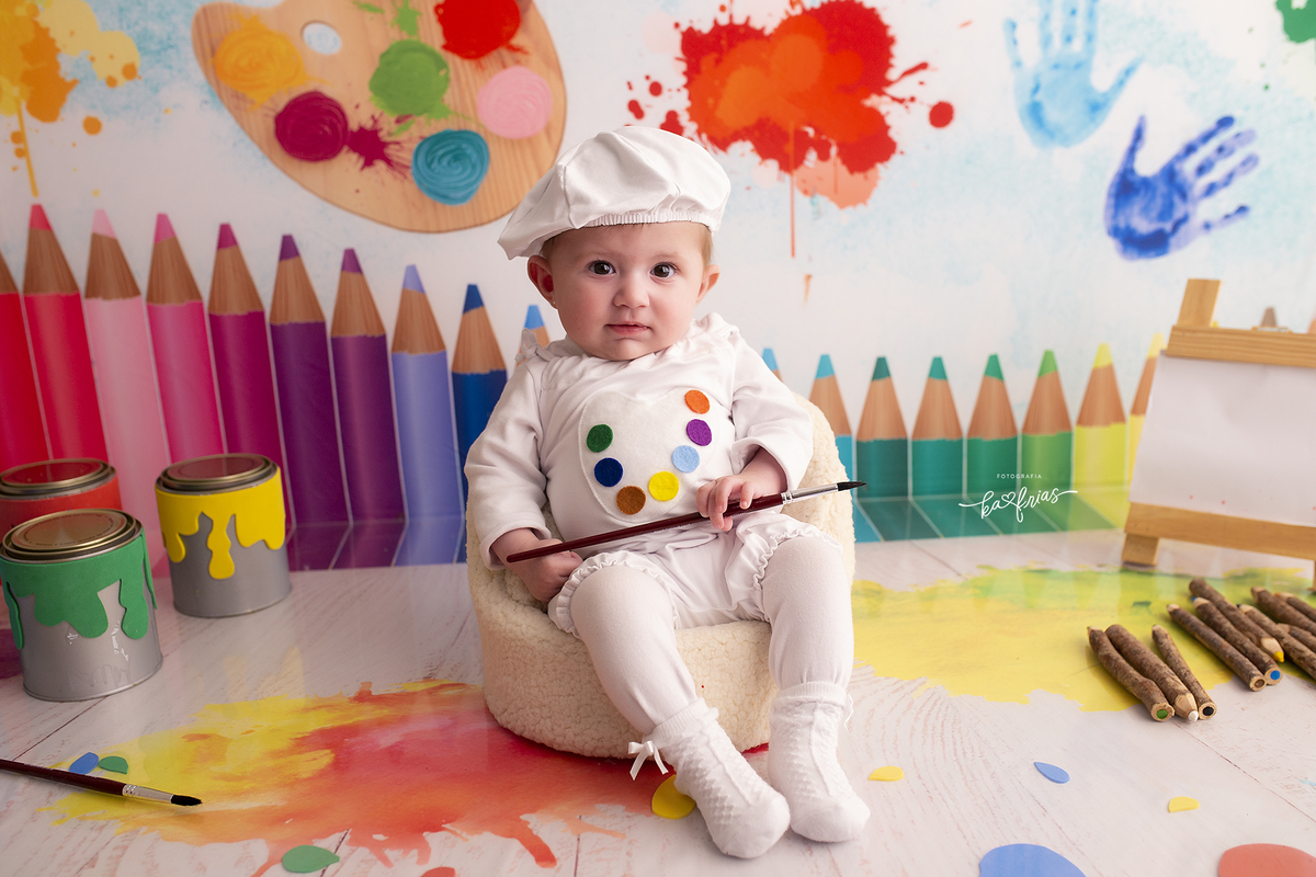 a menina segura o pincel no ensaio de acompanhamento mensal