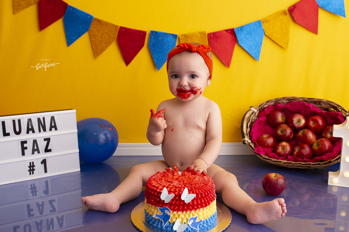 a menina se suja com o bolo no ensaio smash the cake