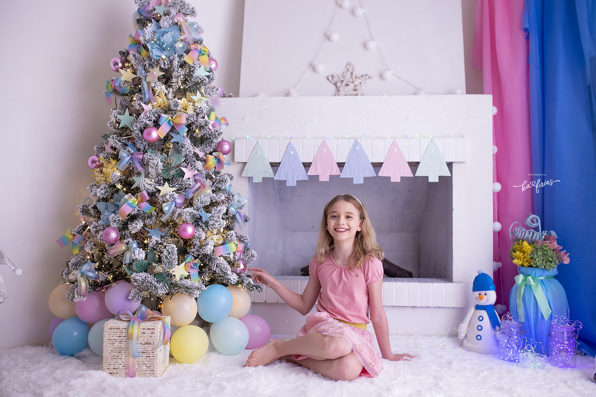 a menina posa ao lado da arvore de natal