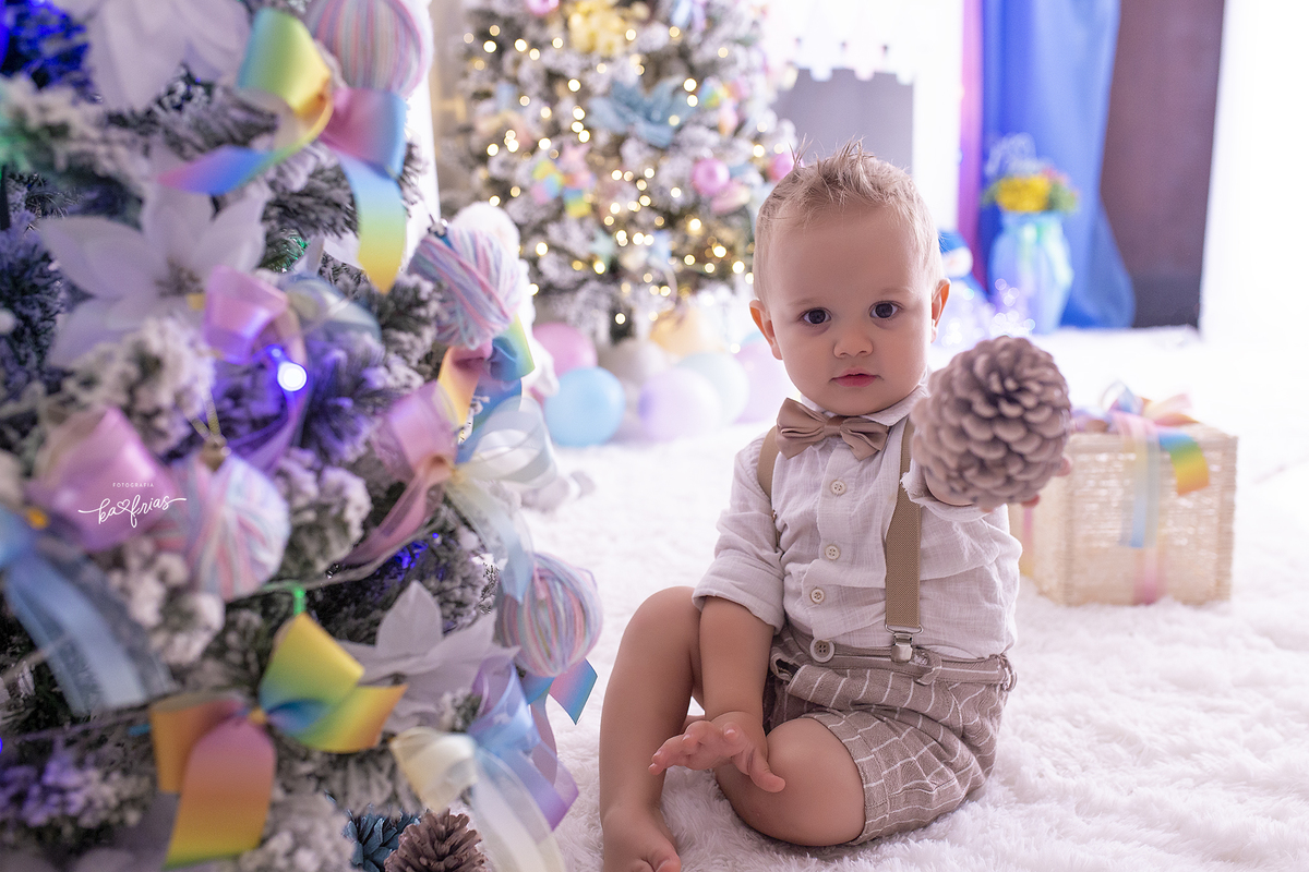 o bebe brinca na arvore de natal