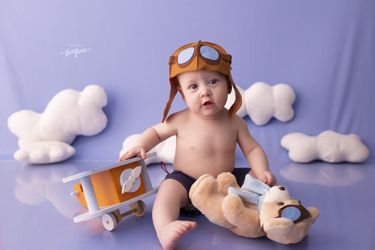 o menino esta vestido de aviador no ensaio de 07 meses