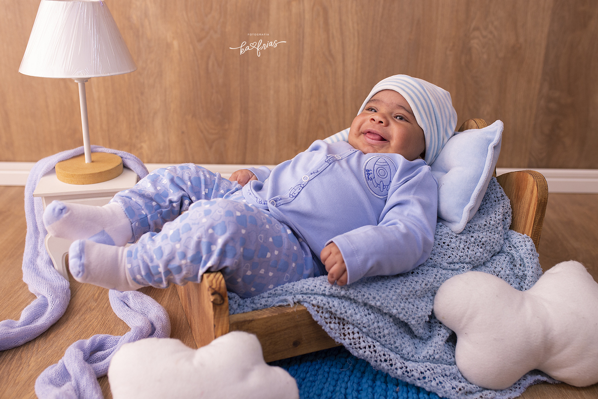 o menino esta deitado na cama para as fotos mensais