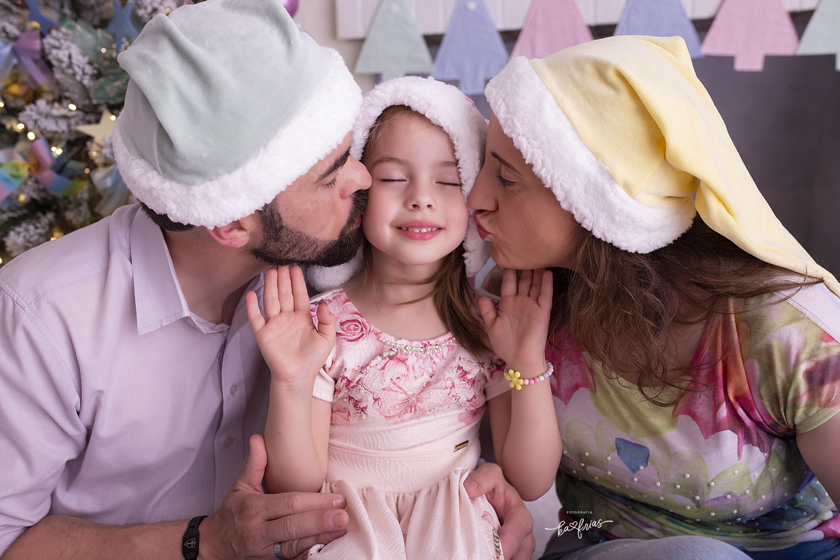 a menina recebe o beijo dos pais na sessão