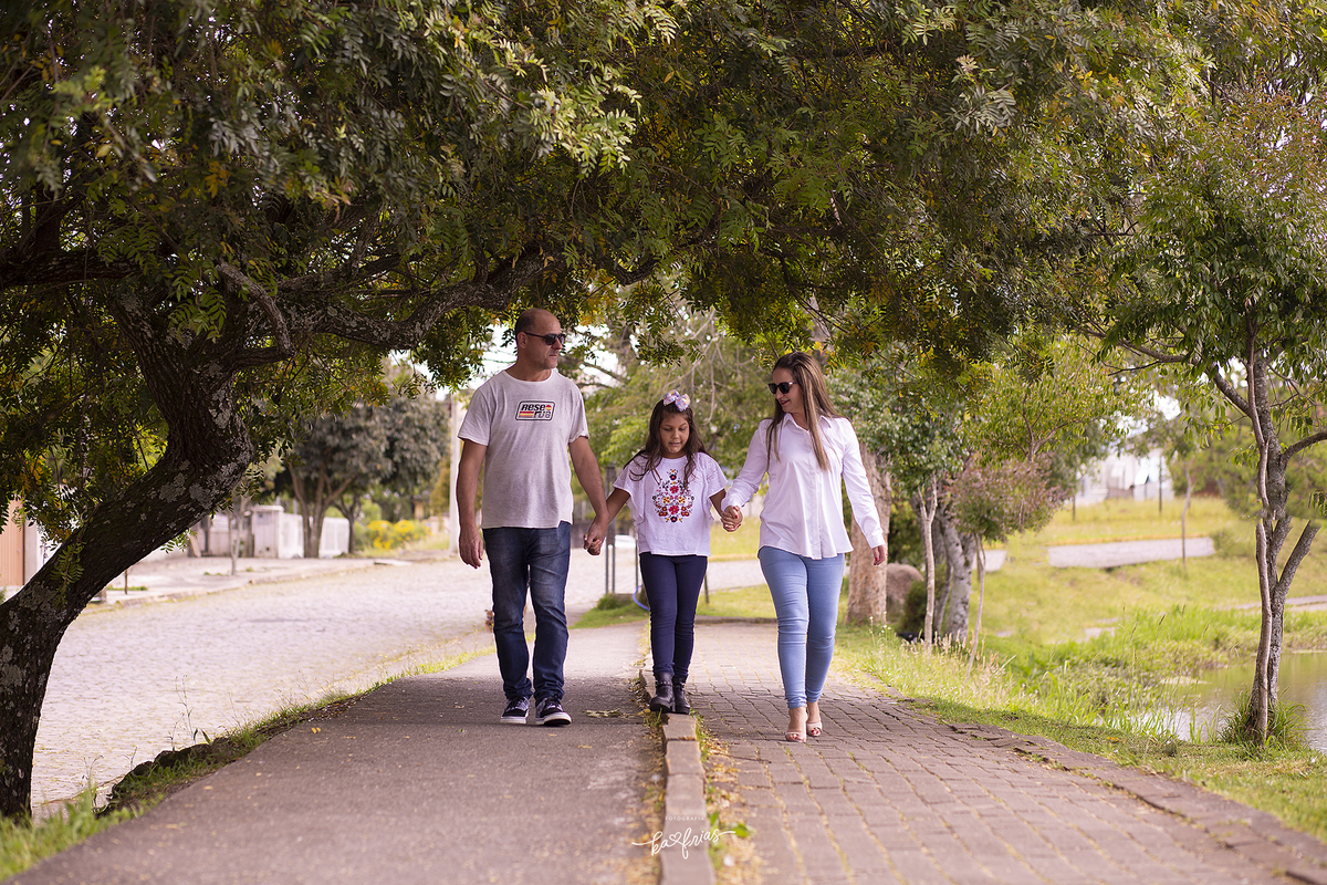 os pais caminham com a filha no ensaio externo