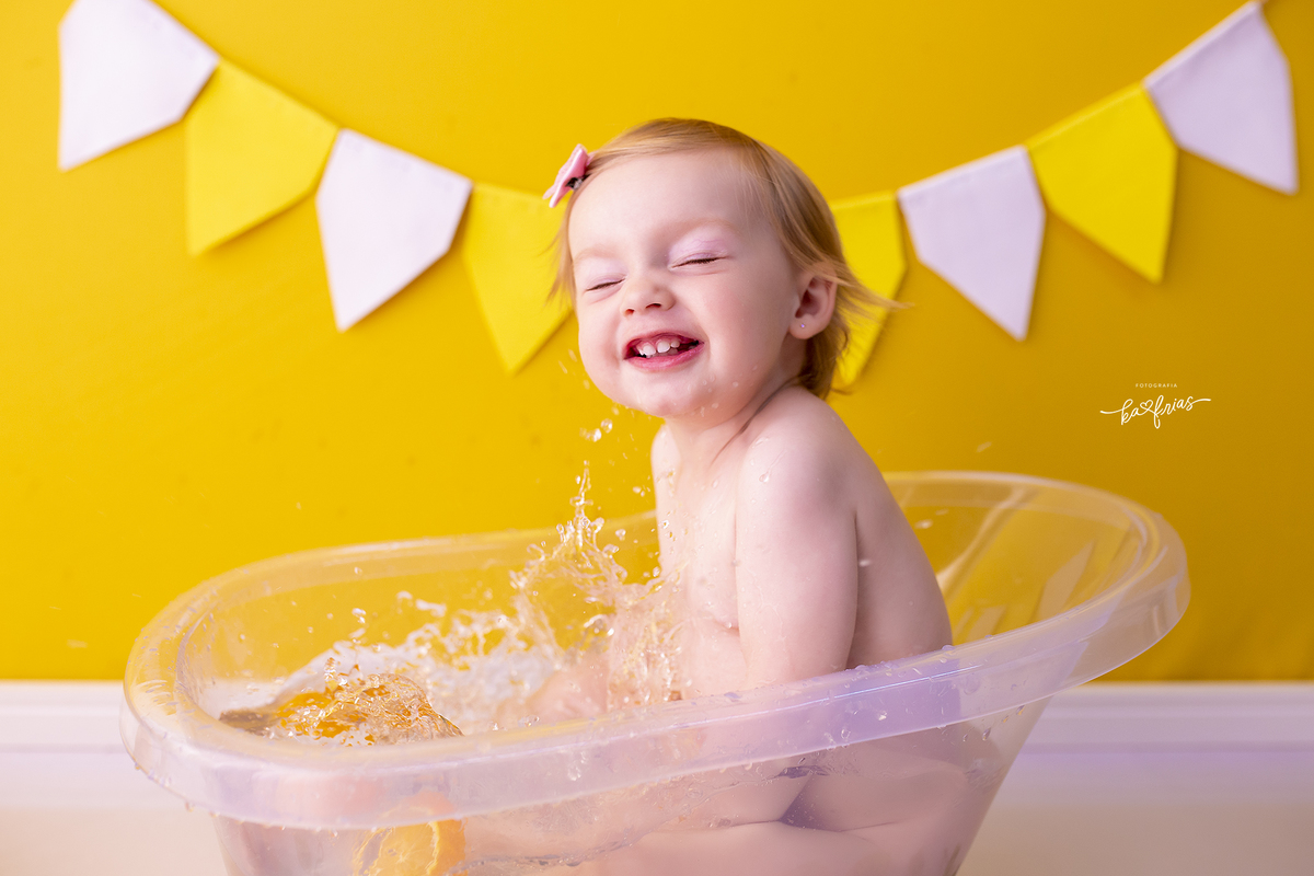 no ensaio infantil a bebe joga agua para fora da banheira