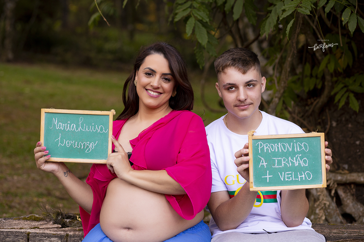 mae e filho seguram a placa como acessorio no ensaio de gestante