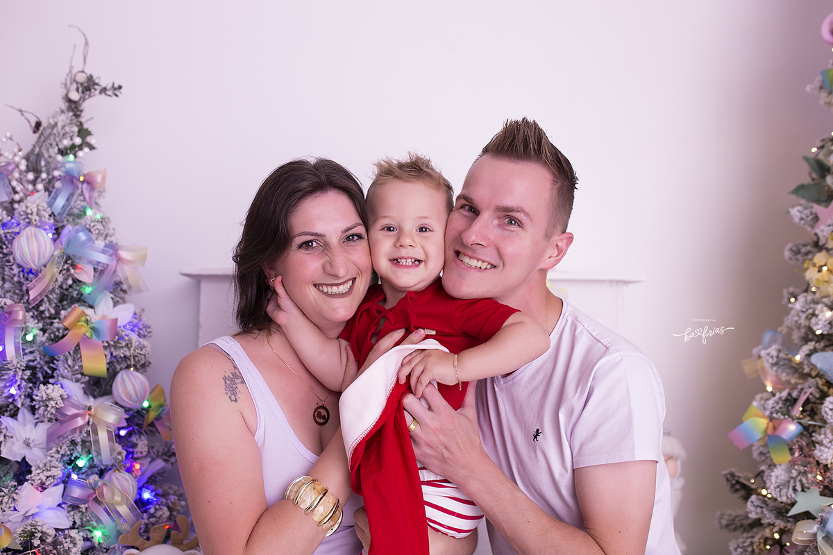 o bebe abraça os pais no ensaio de natal