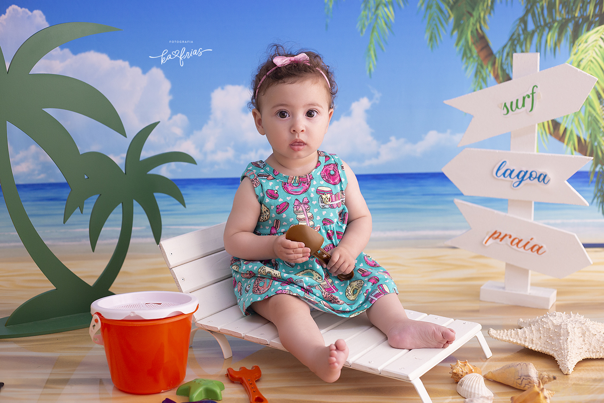 a bebe esta sentada no cenario de praia