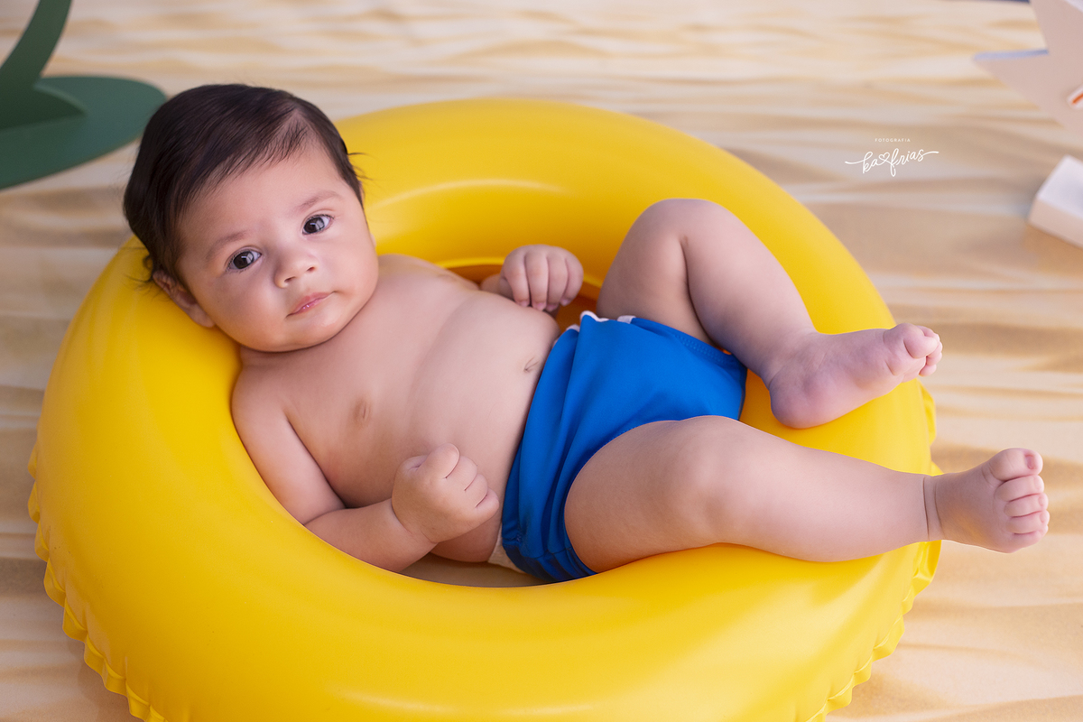 o menino esta deitado na boia para as fotos de praia