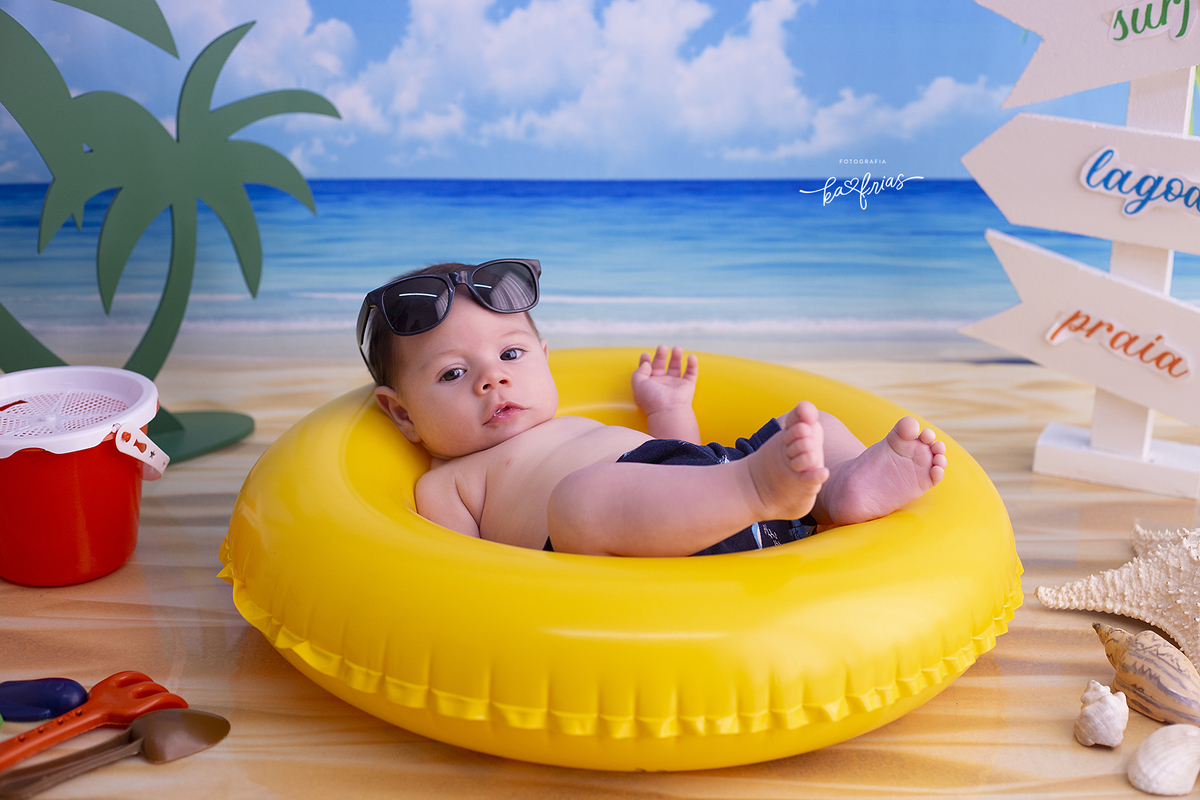 o menino esta deitado na boia para suas fotos mensais