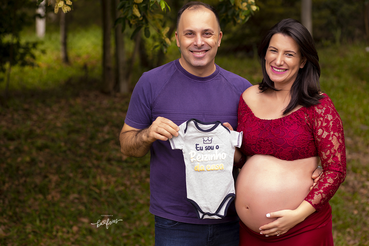 no ensaio externo de gestante, os pais levaram roupinhas do bebe