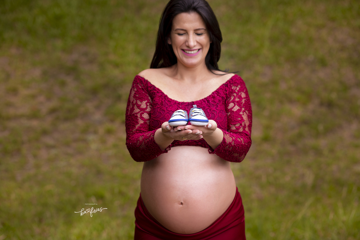 a gestante segura o sapatinho nas fotos externas
