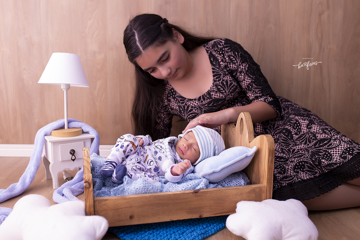 a irmã faz carinho no bebe enquanto ele dorme