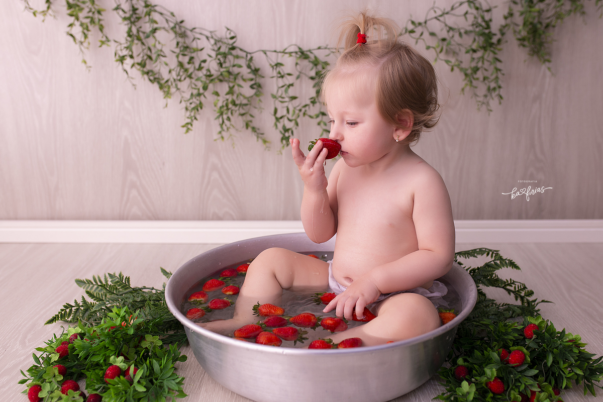 a bebe cheira o morango no ensaio infantil