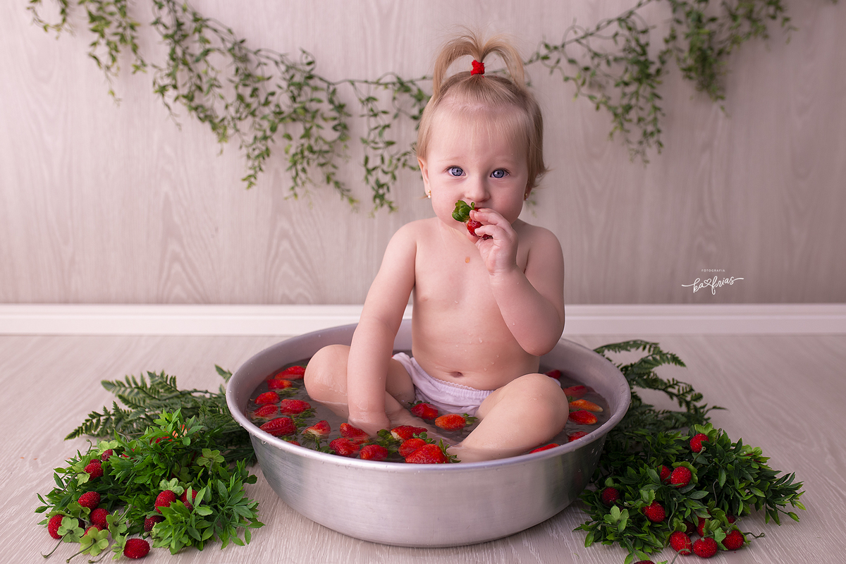 a menina esta dentro da bacia para a sessão de seu um aninho