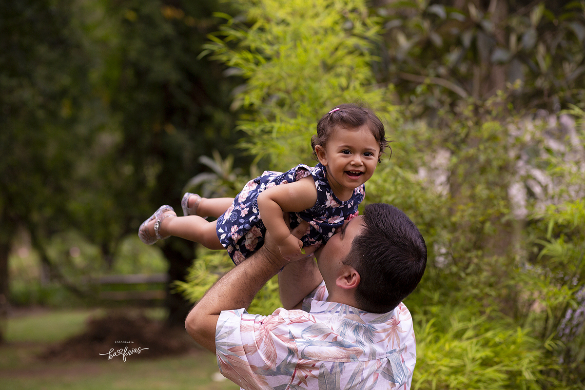 o pai brinca com a filha durante sessão de fotos