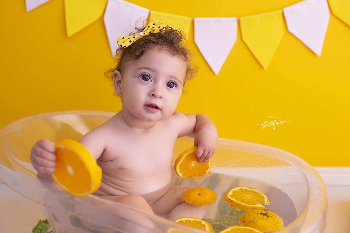 a menina brinca com as laranjas no ensaio infantil