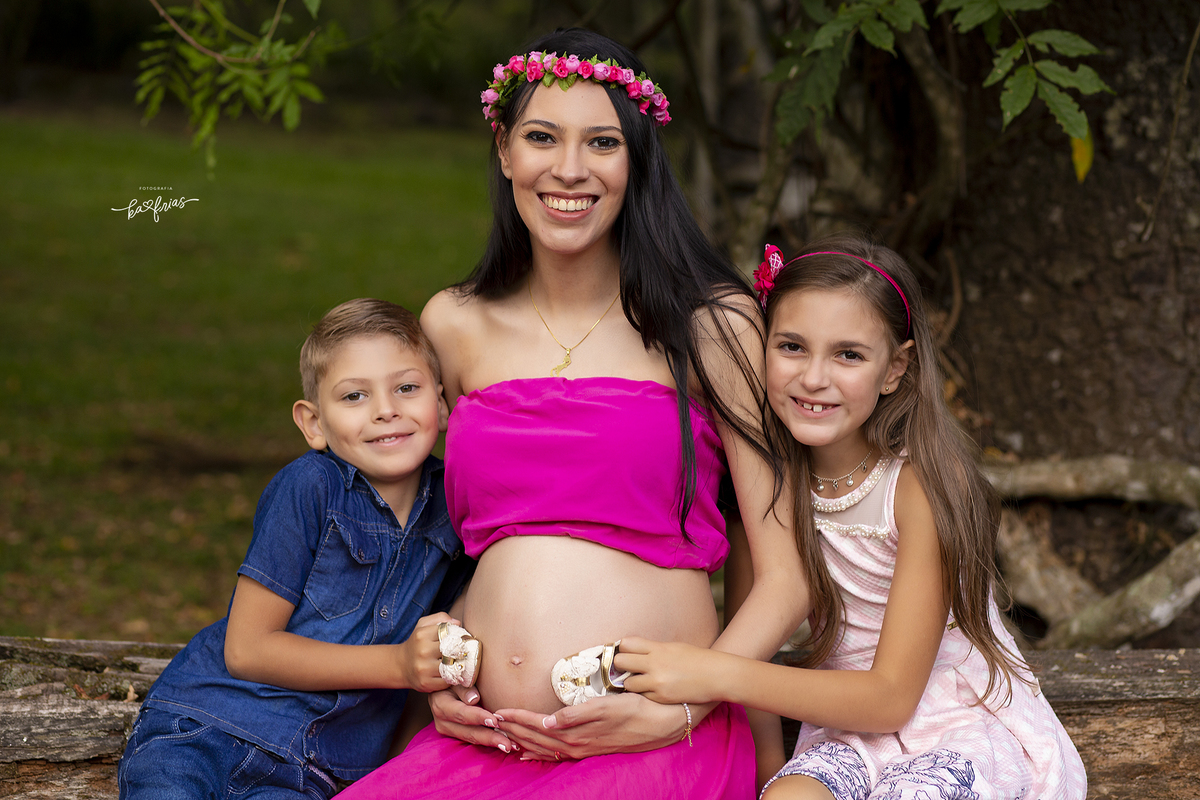 os irmaos seguram o sapatinho da bebe nas fotos externas