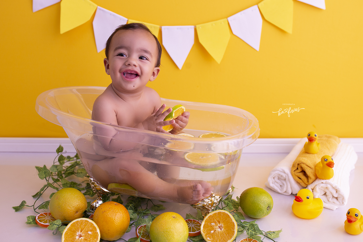 o bebe esta na banheira de laranjas para suas fotos de acompanhamento mensal