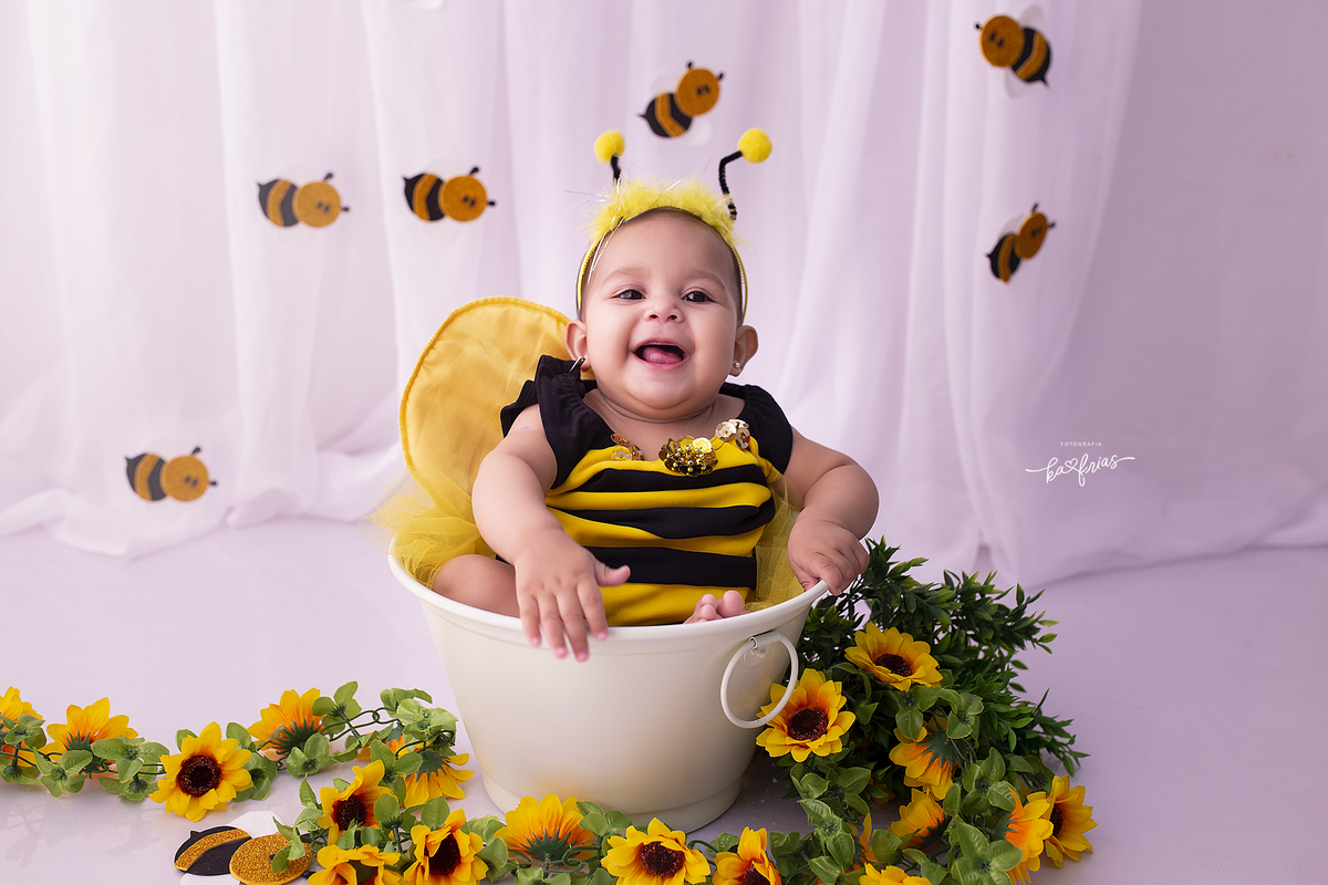 a menina esta dentro do baldinho no ensaio infantil