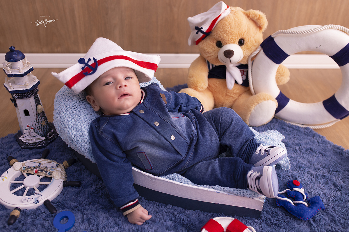 o menino esta vestido de marinheiro para as fotos mensais