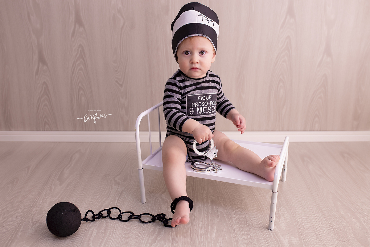 no ensaio infantil o bebe esta vestido de presidiario