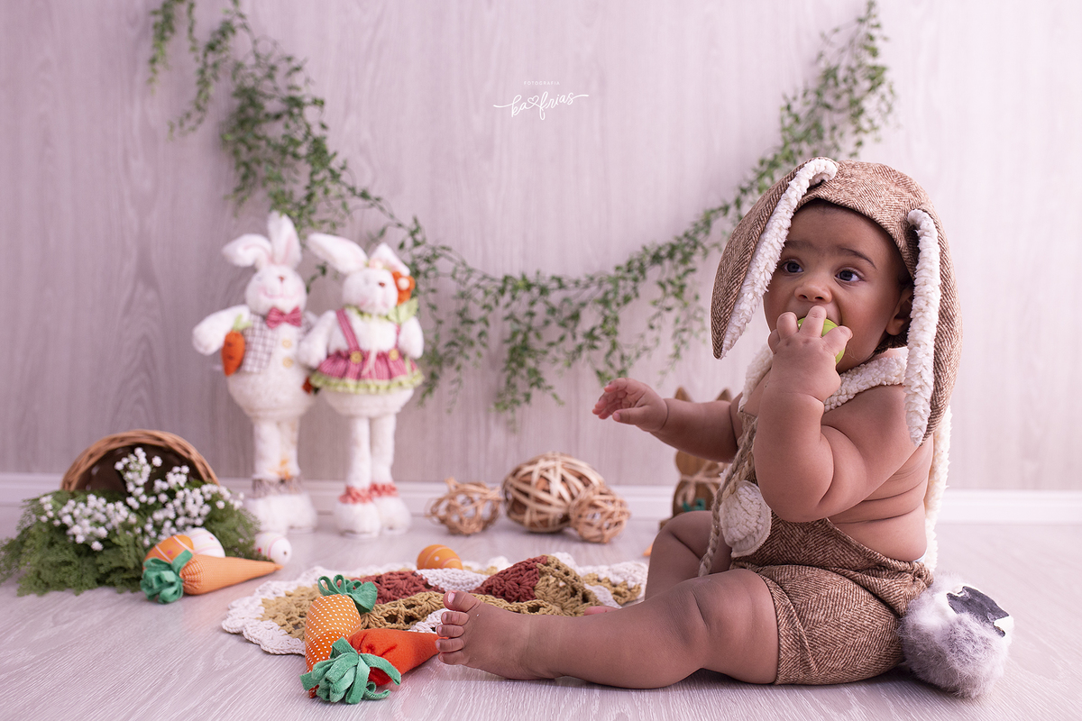 o menino esta vestido de coelho para as fotos mensais