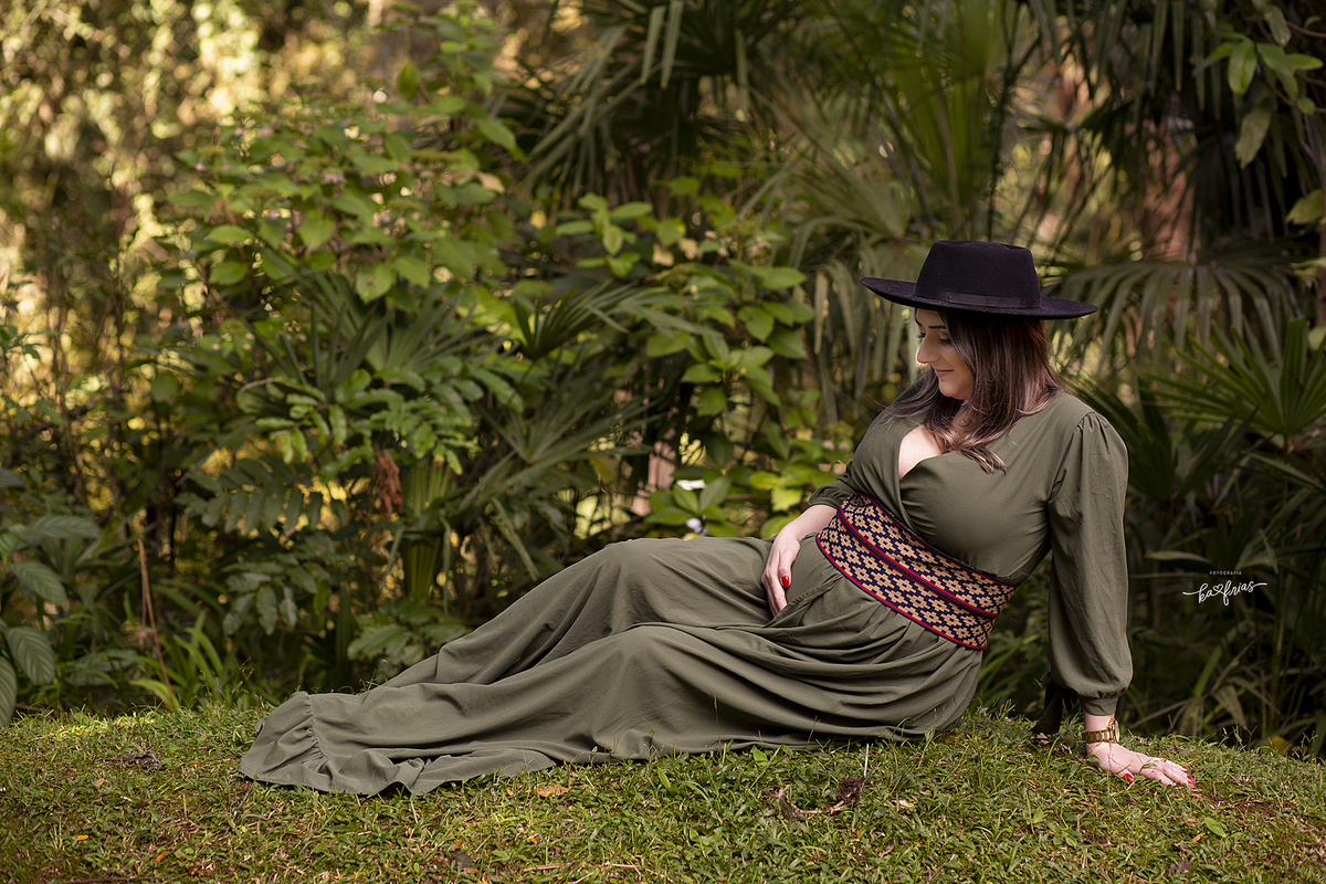 a gestante olha para a barriga na sessão de fotos