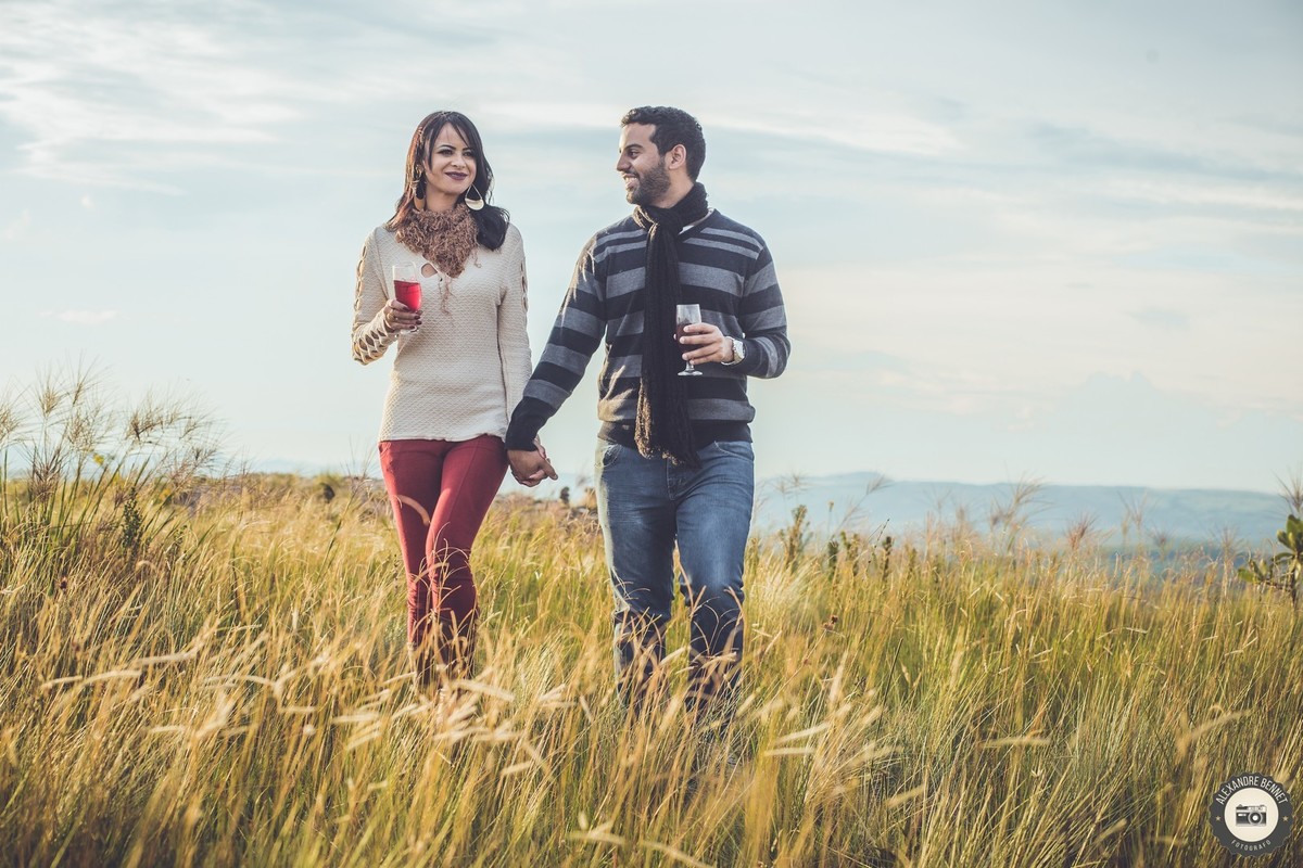 Casal caminha com duas taças de vinho nas mãos em monte da cidade de carrancas 