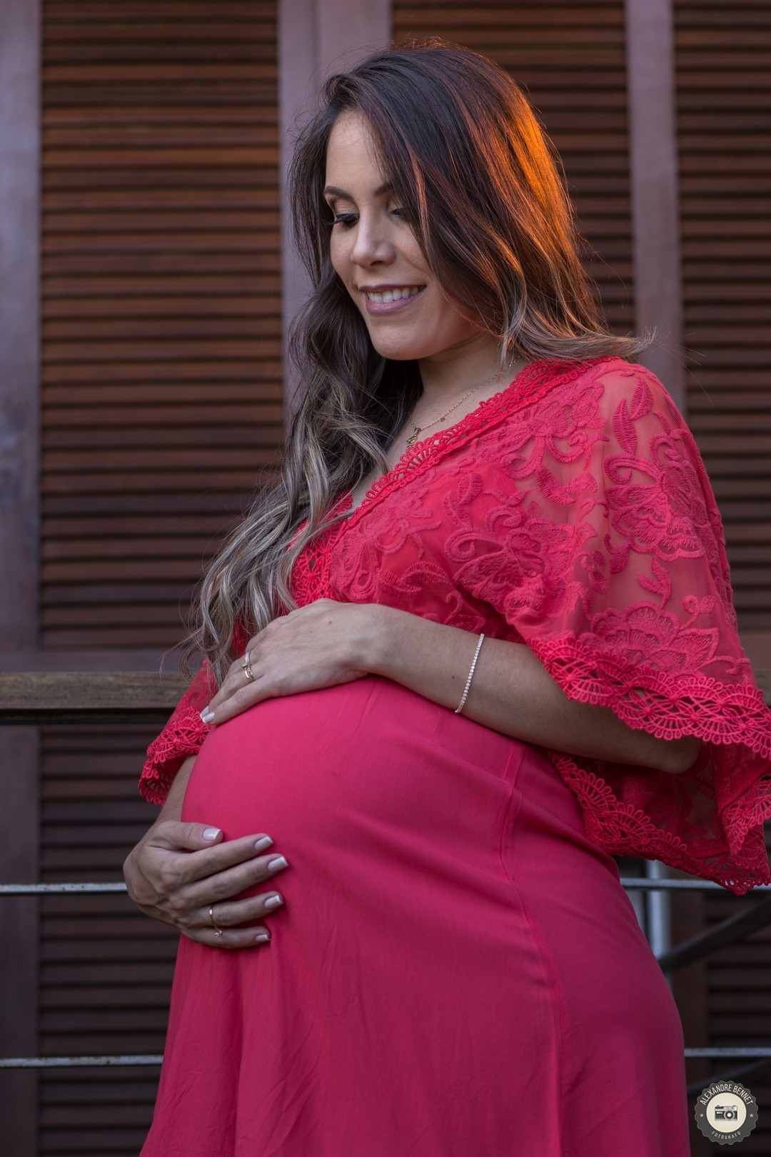 Gestante põe as mãos sobre a barriga e sorri pensando em seu filho