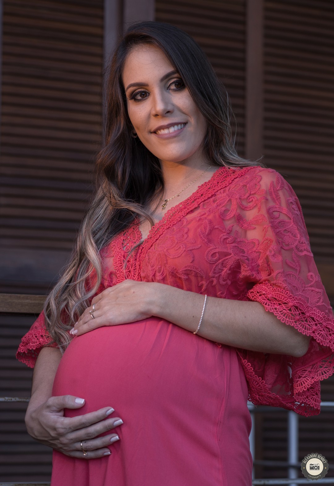 Gestante põe as mãos sobre a barriga e sorri pensando em seu filho