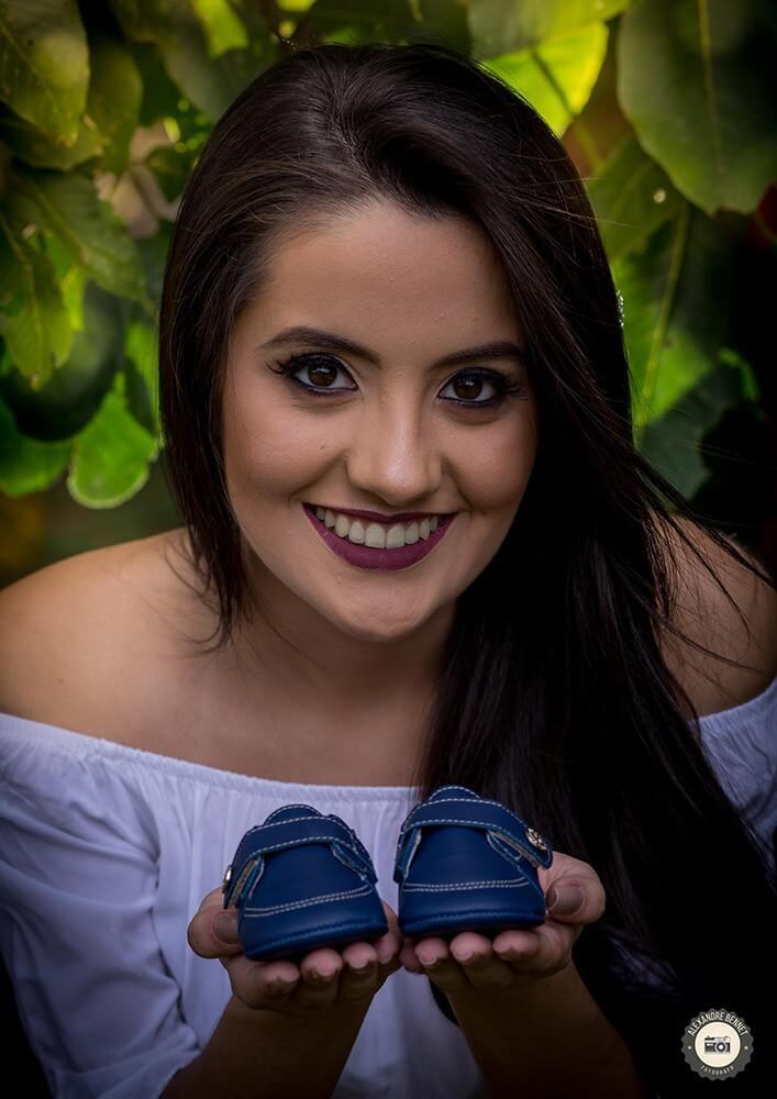 Segurando os sapatinhos do bebê a futura mamãe sorri