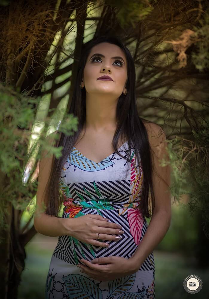 Olhando pro alto com as mãos na barriga a mãe imagina seu futuro bebê