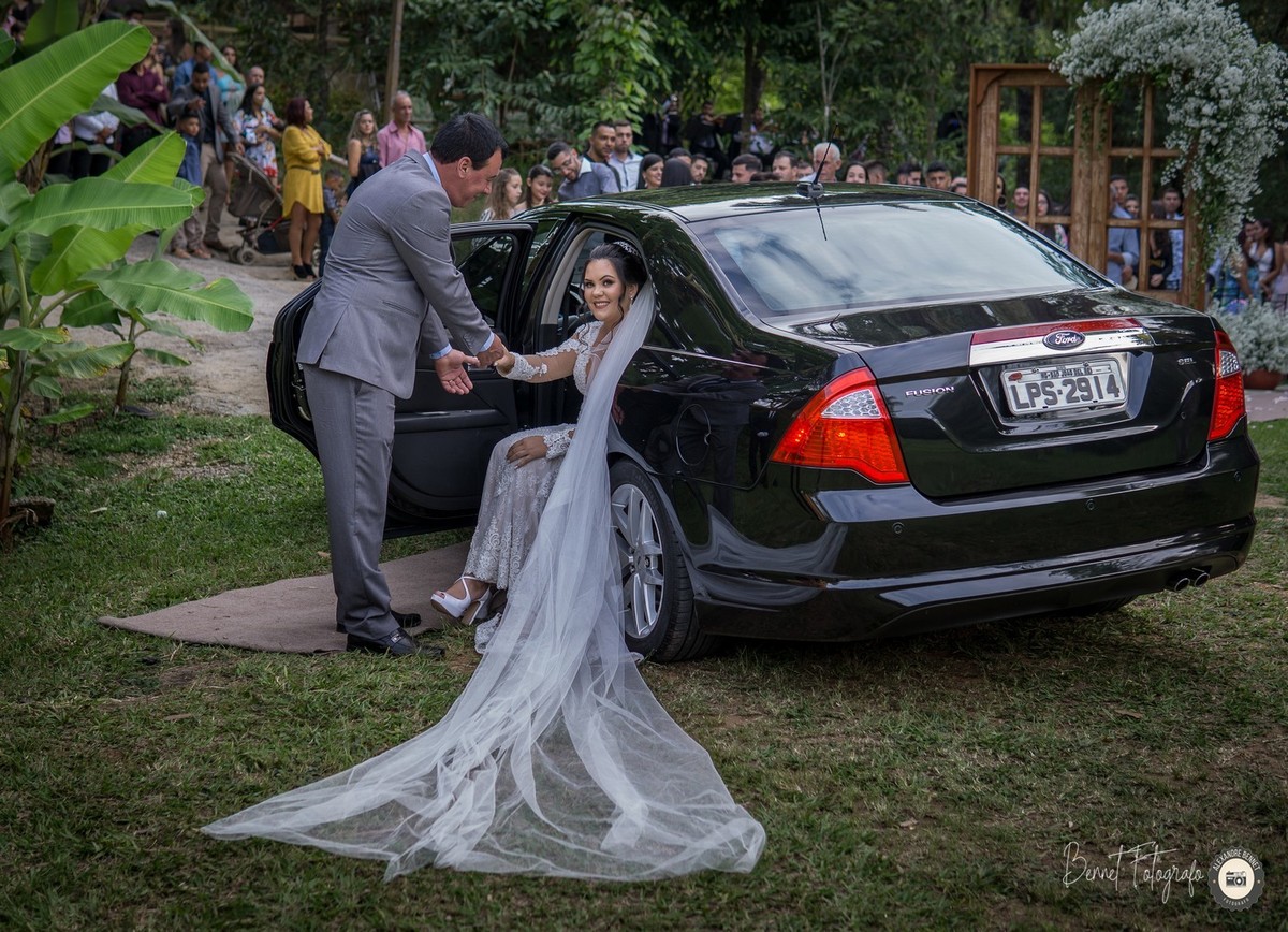 Pai ajuda a noiva a sair do carro para acompanhá-la até o altar onde seu noivo a espera 