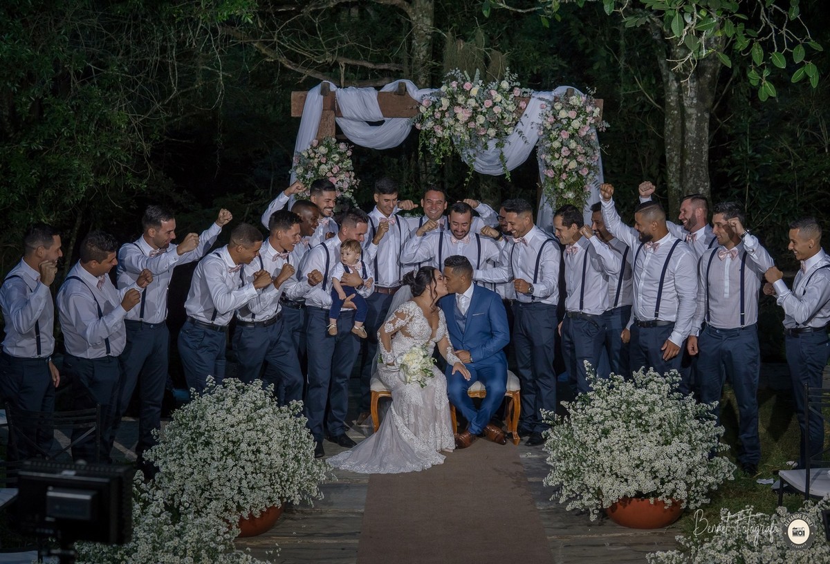 Padrinhos observam o beijo do noivo e da noiva e comemoram felizes pelo casal 