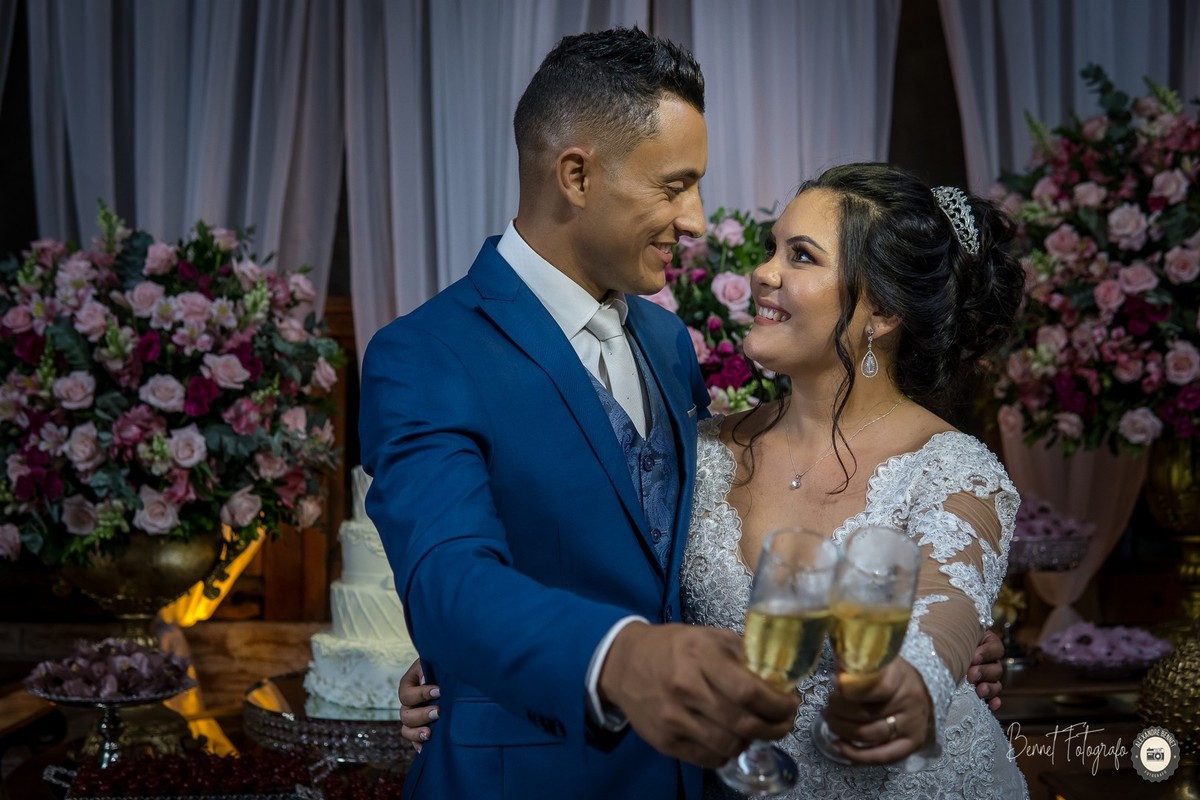 Casal se olha em uma bela pose com as taças de champanhe na mão 