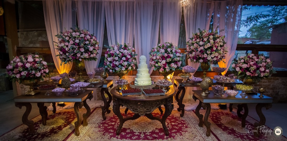 Magnífica mesa do bolo com vários arranjos e docinhos parte mais bonita da decoração